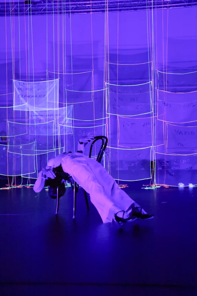 Britta performing the chair dance in blacklight, Tanzfabrik Berlin, June 2021 – photo by Anja Weber